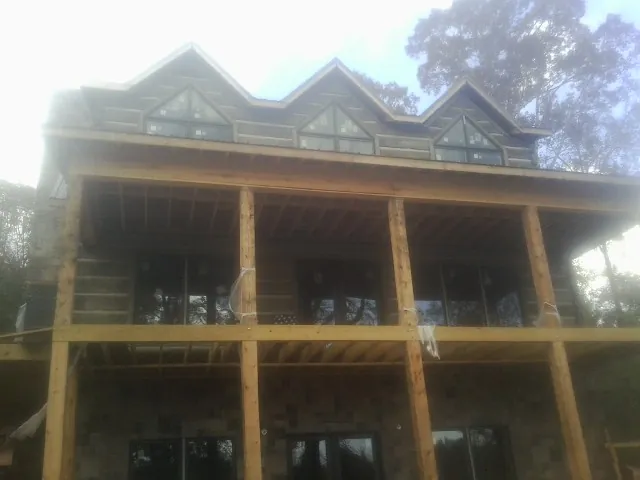 Dormers and porch framing on a large log home under construction — Roof Coating work by our crew in Boston