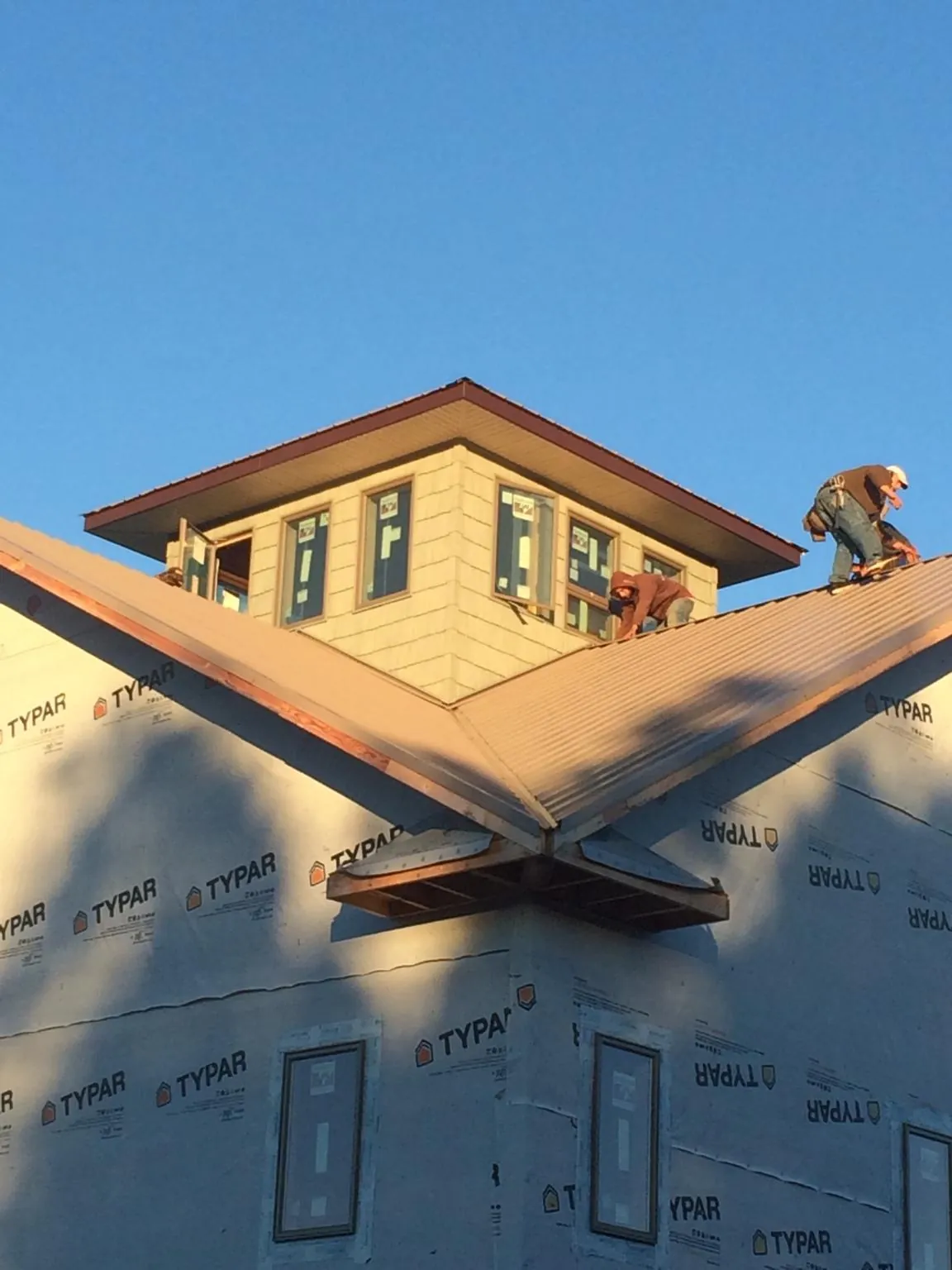Roofers working around a rooftop cupola on a new metal roof at sunset — Roof Waterproofing in Boston by Roofing Brothers